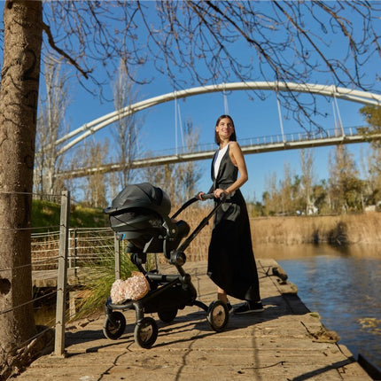 Woman and Mima iZi GO Modular X1 Car Seat on riverside path.