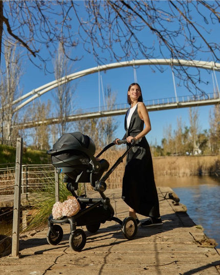 Woman and Mima iZi GO Modular X1 Car Seat on riverside path.