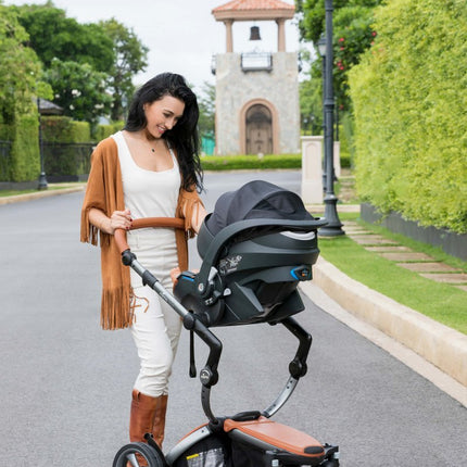 Woman checking on baby in Mima iZi GO Modular X1 Car Seat on street.