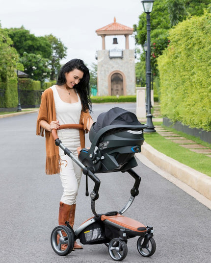 Woman checking on baby in Mima iZi GO Modular X1 Car Seat on street.