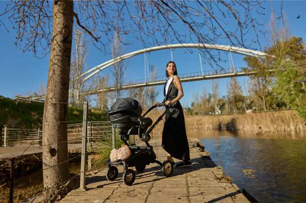 Woman and Mima iZi GO Modular X1 Car Seat on riverside path.