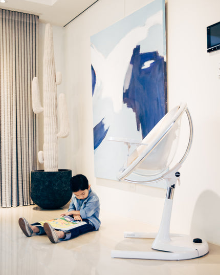 Boy sitting in a living room close to the Mima Moon High Chair