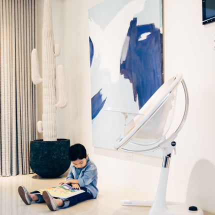 Boy sitting in a living room close to the Mima Moon High Chair