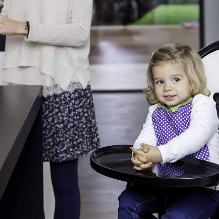 Child seated comfortably in a Mima Moon High Chair during meal time.