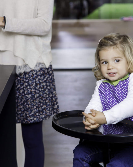 Child seated comfortably in a Mima Moon High Chair during meal time.