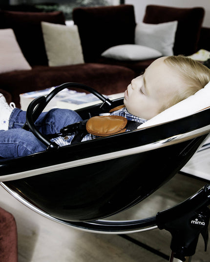 Mother adjusting a Mima Moon High Chair for her sleeping baby.