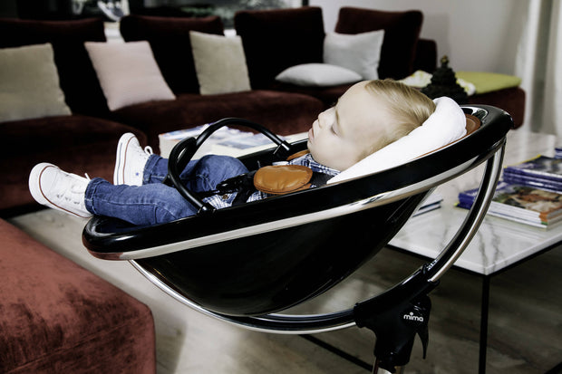 Mother adjusting a Mima Moon High Chair for her sleeping baby.