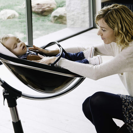 Mother checking on her sleeping baby in a Mima Moon High Chair.