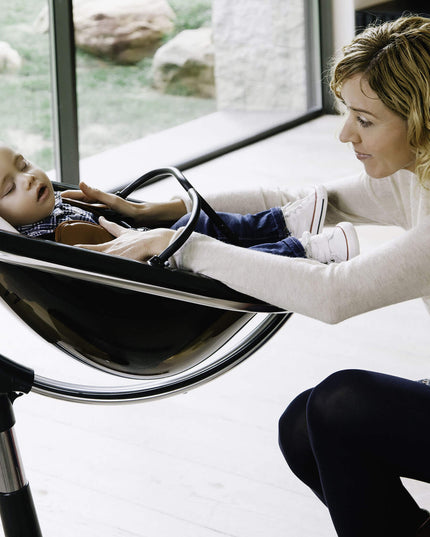 Mother checking on her sleeping baby in a Mima Moon High Chair.