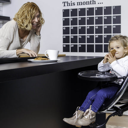 Mother and child interacting over a counter, child sitting in a Mima Moon High Chair.