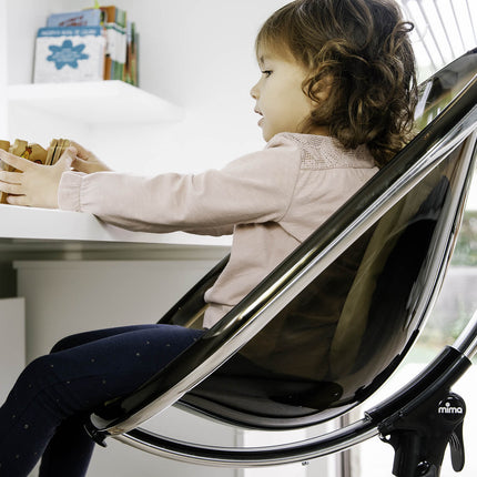 Toddler asleep in a Mima Moon High Chair in a cozy living room.