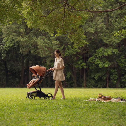 Woman pushing Mima XARI MAX stroller in a grassy park