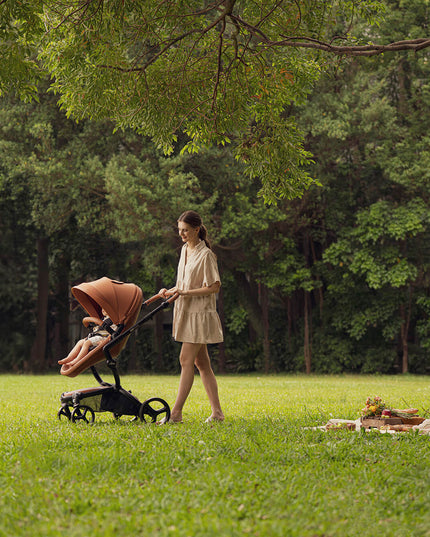 Woman pushing Mima XARI MAX stroller in a grassy park