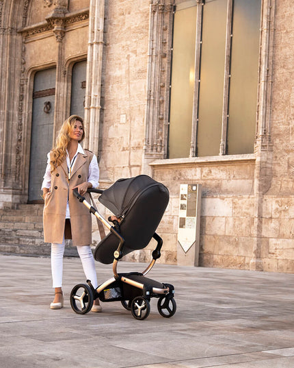 Mother and child with Mima XARI MAX stroller on sunny urban street.