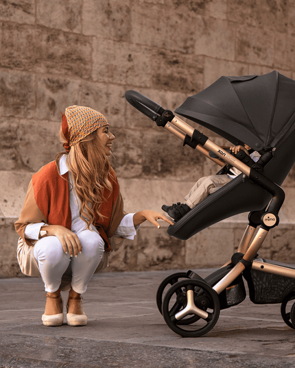 Mother pushing Mima XARI MAX stroller in front of historic stone facade.