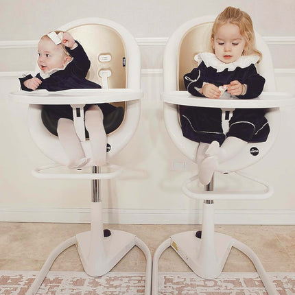 Two toddlers in matching outfits sitting in Mima Moon High Chairs.