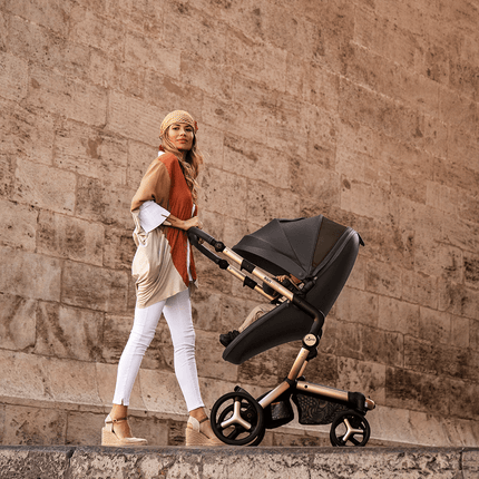 Woman in headscarf pushing Mima XARI MAX stroller in historic urban setting.