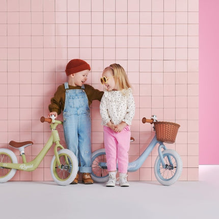 Two children smiling beside Kinderkraft Balance Bike RAPID.