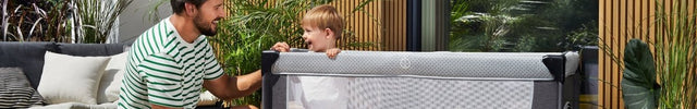 Father and child interacting beside Kinderkraft Travel Cot LEODY outdoors